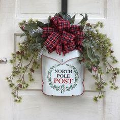 the north pole post sign is decorated with greenery and bows on it's front door