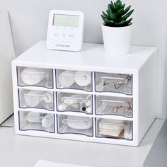 a white desk with several drawers and a clock on it's side, next to a laptop