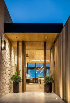 the entrance to a modern home with large windows and wooden columns on either side of it