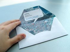 a person is holding an envelope with a business card attached to it, on top of a table