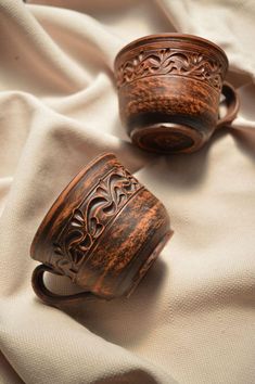 two brown cups sitting on top of a white cloth