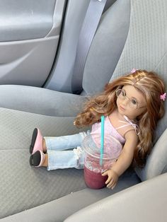 a doll sitting in the back seat of a car holding a drink and wearing glasses