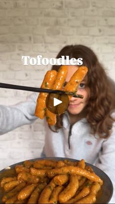 a woman is holding up some food in front of her face with chopsticks