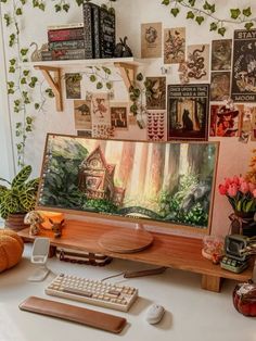 a desk with a computer, keyboard and various pictures on the wall in front of it