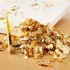 a pile of gold flakes next to a brush