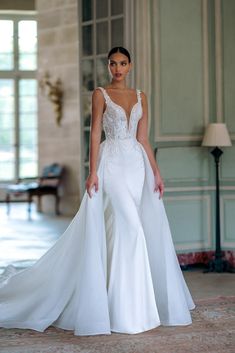 a woman in a white wedding dress posing for the camera with her long train on