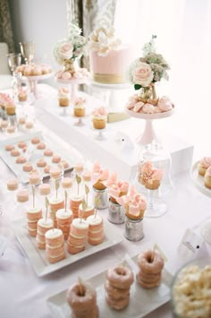 a table topped with lots of pink and white desserts