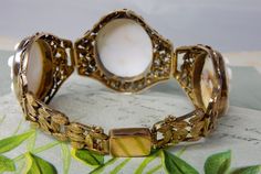 "Here's an antique carved shell cameo bracelet, set in 10k gold. It features 3 cameos, the middle one being larger than the two on the sides. The setting has a delicate openwork construction of leaves, mounted onto a wire backing. The center link is 1.1/2\" wide, and the two sides are 1.1/4\". It has a hidden box clasp and safety chain, and is stamped, '10k' on the back of the clasp. Interior circumference is 7\". Completely original with no repairs and no damage. Thanks for looking." Antique White Bracelet Jewelry, White Antique Bracelet Jewelry, Ornate Cameo Jewelry For Formal Occasions, White Antique Bracelet, Antique Oval Gold Bracelet, Antique Intaglio Bracelets As A Gift, Oval Cameo Bracelet For Formal Occasions, Antique Cameo Bracelet For Wedding, Antique Oval Engraved Bracelets