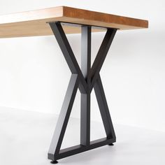 a wooden table with black metal legs and a wood slab on the top that is shaped like an x