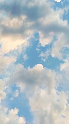 the airplane is flying high in the sky with some clouds above it on a sunny day