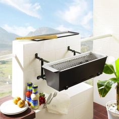 an outdoor bbq grill sitting on top of a table next to a potted plant