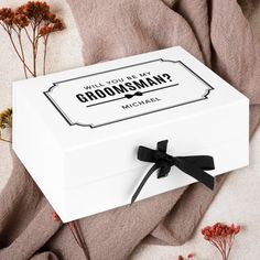 a white box with a black bow on it that says will you be my groomsman?