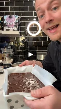 a man is holding up a chocolate cake