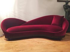 a red couch sitting on top of a hard wood floor