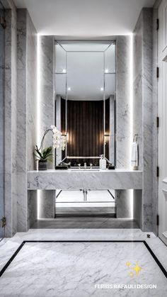 an elegant bathroom with marble floors and walls, along with a large mirror on the wall