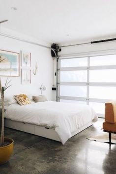 a bedroom with a bed, chair and pictures on the wall above it in front of a sliding glass door