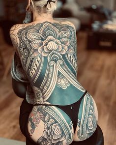 the back of a woman's body with tattoos on her upper and lower half