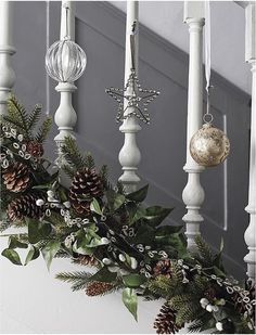 christmas garland with pine cones and ornaments hanging from the banisters