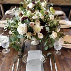 the table is set with white and red flowers, silverware, and napkins