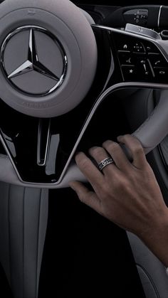 a man is holding the steering wheel controls in a mercedes car, while wearing a ring