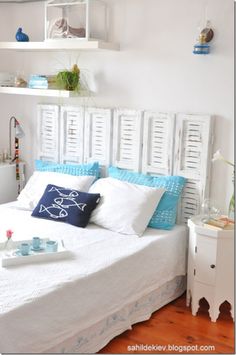 a white bed with blue and white pillows on it's headboard, in a bedroom