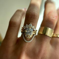 a woman's hand with two gold rings on it and a diamond ring in the middle