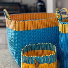 two blue and yellow baskets sitting next to each other on top of a kitchen counter