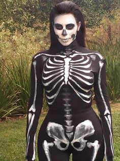 a woman in skeleton costume standing on grass