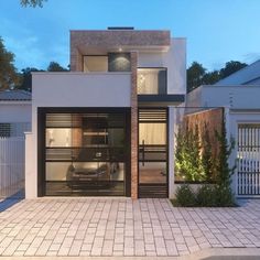 an image of a modern style house with glass doors and brick walkways in the front yard