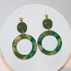 "If you're looking for statement earrings to dress up an outfit, this pair is for you! Handcrafted from polymer clay with shades of green and hints of gold, this one of a kind pair is topped off with a resin finish to give them a classy shine.  2.5\" drop length Made with plastic hooks that are perfect for people with sensitive ears or metal allergies. Other pieces of the earring may be metal but do not touch the earlobe. Due to the color differences in computer monitors the colors might be slig Green Pierced Everyday Earrings, Green Pierced Earrings For Everyday, Everyday Green Circular Earrings, Green Dangle Hoop Earrings Hypoallergenic, Green Hypoallergenic Drop Earrings, Hypoallergenic Green Drop Earrings, Small Drawstring Bag, Green Gift, Fall Earrings