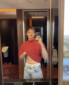 a man taking a selfie in front of a mirror with his shirt off and jeans on