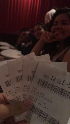 some people are sitting in a theater and one person is holding three tickets