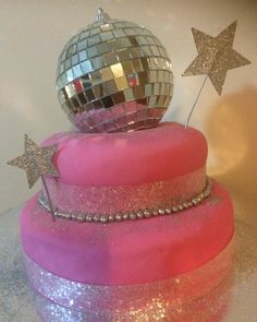 there is a pink cake that has a disco ball on top and stars around it