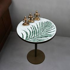 a small table with two teapots on it and a fern leaf design top