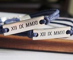 two personalized bracelets sitting on top of a wooden board with metal clasps