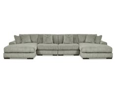 a large sectional couch with pillows on the top and bottom corner, in light gray