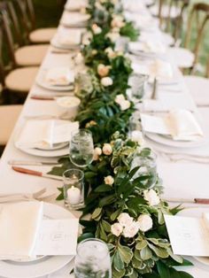 the long table is set with white plates and silverware