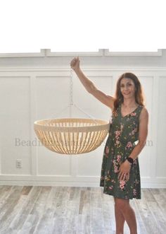 a woman standing in front of a chandelier with one arm raised and the other hand up