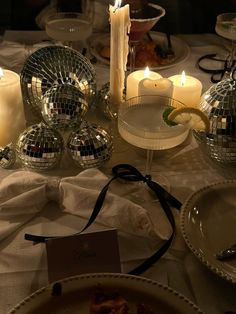 a table topped with plates and candles next to disco ball dishes on top of a table