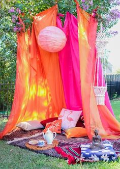 an orange and pink tent sitting on top of a lush green field