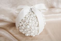 a white ornament with pearls and a bow on a bed sheet for decoration