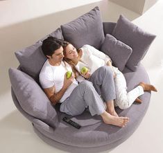 a man and woman sitting on a bean bag chair in the middle of a room