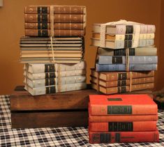 a stack of books sitting on top of a wooden box next to a pile of other books