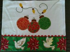 a towel with christmas ornaments on it and two white doves hanging from the side