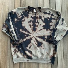 a black and white tie - dyed sweatshirt laying on a wooden floor