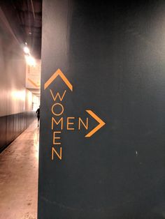 a sign that says women on it next to a wall with an arrow in the middle