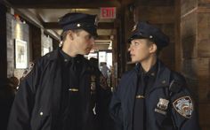 two police officers are talking to each other in a hallway with wooden walls behind them