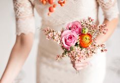 a woman in a white dress holding a bouquet of pink and orange flowers on her wedding day