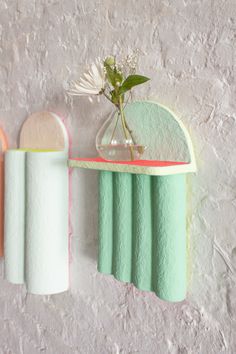 two vases with flowers are hanging on the wall next to toilet paper rolls and towels