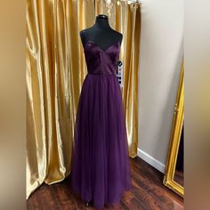 a purple dress is on display in front of a gold curtained room with a mannequin